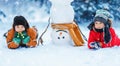 Children lying on the snow near a funny snowman Royalty Free Stock Photo