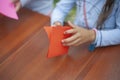 Children make origami out of paper. Child bends colored paper on table. Background creativity lesson for kids