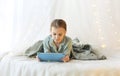 Little girl using digital tablet while lying on canopy princess bed decorated with xmas lights Royalty Free Stock Photo