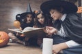 Children in monster costumes sat on the floor, cross-legged and with curiosity consider a spellbook Royalty Free Stock Photo