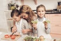 Children with mother in kitchen. Mother is helping kids prepare vegetables for salad. Royalty Free Stock Photo