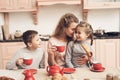 Children with mother in kitchen. Family is drinking tea with croissants.