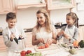 Children with mother in kitchen. Family is preparing vegetables for salad. Royalty Free Stock Photo