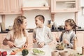 Children with mother in kitchen. Kids are helping mother to make salad. Royalty Free Stock Photo