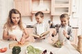 Children with mother in kitchen. Kids are helping mother to make salad. Royalty Free Stock Photo