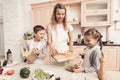 Children with mother in kitchen. Kids are helping mother to make salad. Royalty Free Stock Photo