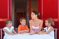 Children and mother sit on verandah round table