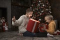 Children near Christmas tree with gift boxes. Two brothers open with New Years gifts. Kids opening Xmas presents Royalty Free Stock Photo