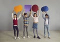 Group of happy little school children holding up multicolored paper speech balloons Royalty Free Stock Photo