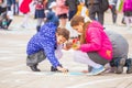 Children paint with colored chalk on asphalt on a city holiday