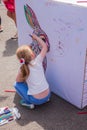 Children paint on the street. On a sunny summer day, a girlie in a white T-shirt draws with felt-tip pens.