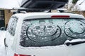 Children painted a smiling face on the snow-covered windows of the car. Family vacation during the winter holidays Royalty Free Stock Photo