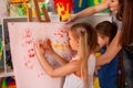 Children painting finger on easel. Group of kids with teacher. Royalty Free Stock Photo