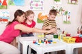 Children painting with teacher in art class.