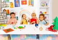 Children painting together New Year balls and sit