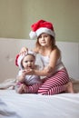 Children in pajamas and Christmas caps playing on the bed