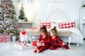 Children in pajamas unwrap presents early Christmas morning on the floor