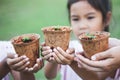 Children and parent hands holding young seedlings in recycle fiber pots together for planting in garden