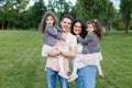 Children with parents in the park. Cute family haming fun in nature. Twin toddler sisters holding parents. Happy family concept