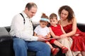 Children with parents read book on sofa