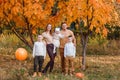 Children and parents stand against the background of yellow mountain ash in the autumn in October. orange pumpkin