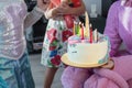 Children party entertainer gives tasty bright cake decorated in form of fantasy unicorn for kid celebrating birthday with friends