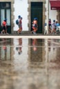 Children passing by in the reflection of wet pavement, Portuguese street - Vertical