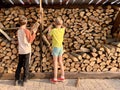 Children pile up chopped dry firewood. Boys on the background of chopped firewood. Lumber for the winter from birch, pine and oak Royalty Free Stock Photo