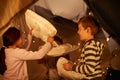 Children, pillow fight and siblings in a fort with funny, playing or bonding at home together. Family, love and kids in Royalty Free Stock Photo