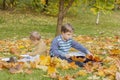 Children play in the autumn Park. The kids throw yellow leaves. Baby boy with a maple leaf. Autumn foliage. Family outdoor