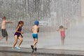 Children play carefree among the refreshing splashes of the summer city fountain. Bathing and rest in your free time in the rays o