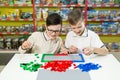 Children play in the designer at the table. Two boys play together with colored plastic blocks in the gaming center