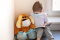 Children play a doctor. A large brown toy in a medical bandage and shoe covers is sitting on the window. A child is reading a book Royalty Free Stock Photo