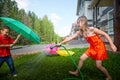 Children playing with garden sprinkler. Brother and sister running and jumping. Summer outdoor water fun in backyard