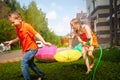 Children playing with garden sprinkler. Brother and sister running and jumping. Summer outdoor water fun in backyard