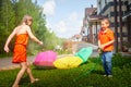 Children playing with garden sprinkler. Brother and sister running and jumping. Summer outdoor water fun in backyard