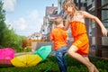 Children playing with garden sprinkler. Brother and sister running and jumping. Summer outdoor water fun in backyard