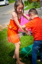 Children playing with garden sprinkler. Brother and sister running and jumping. Summer outdoor water fun in backyard Royalty Free Stock Photo
