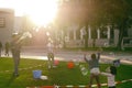 Children play with large soap bubbles on a green lawn near the V Royalty Free Stock Photo