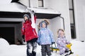 Children play outdoors in snow. Three kids enjoy a sleigh ride. Child sledding in winter against house Royalty Free Stock Photo