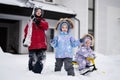 Children play outdoors in snow. Three kids enjoy a sleigh ride. Child sledding in winter against house Royalty Free Stock Photo