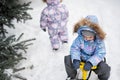 Children play outdoors in snow. Two little sisters enjoy a sleigh ride. Child sledding. Toddler kid riding a sledge. Kids sled in Royalty Free Stock Photo