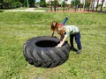 Children play and pick up the tire. Car parts and accessories in a kid`s game. A boy and a girl 6 and 7 years old are doing