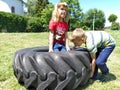 Children play and pick up the tire. Car parts and accessories in a kid`s game. A boy and a girl 6 and 7 years old are doing