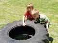 Children play and pick up the tire. Car parts and accessories in a kid`s game. A boy and a girl 6 and 7 years old are doing