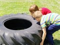 Children play and pick up the tire. Car parts and accessories in a kid`s game. A boy and a girl 6 and 7 years old are doing