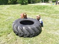 Children play and pick up the tire. Car parts and accessories in a kid`s game. A boy and a girl 6 and 7 years old are doing