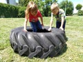 Children play and pick up the tire. Car parts and accessories in a kid`s game. A boy and a girl 6 and 7 years old are doing
