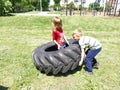 Children play and pick up the tire. Car parts and accessories in a kid`s game. A boy and a girl 6 and 7 years old are doing