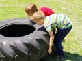 Children play and pick up the tire. Car parts and accessories in a kid`s game. A boy and a girl 6 and 7 years old are doing